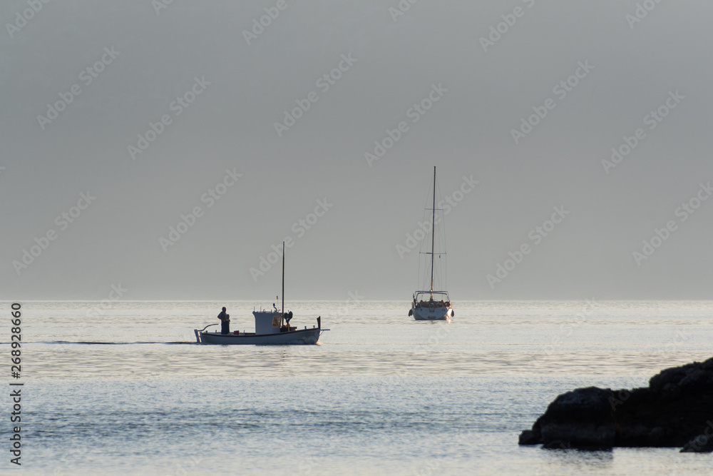 A sailing boat and a fishing boat on the sea