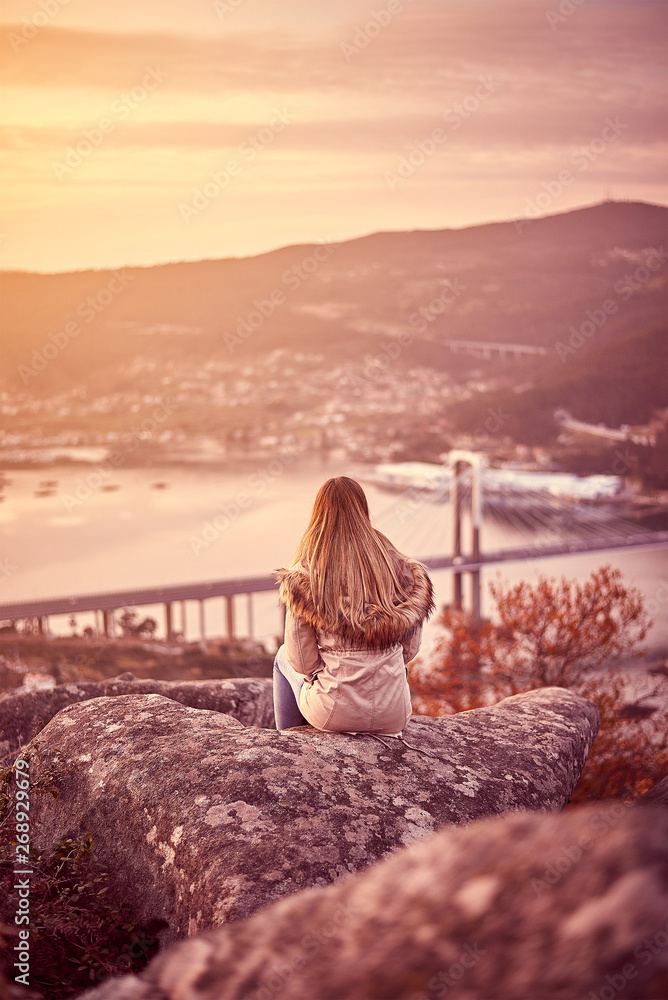 Young woman contemplating Vigo from a rock in a high mount