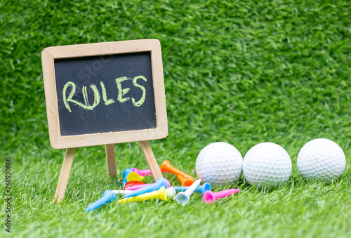 Rules of golf with sign and golf balls are on green grass