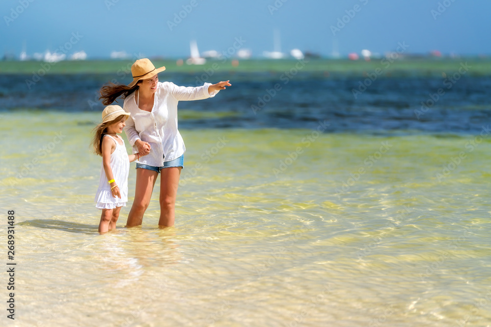 Young mother and little daughter standing on the beach in Dominican Republic Young mother and little daughter standing on the beach in Dominican Republic
