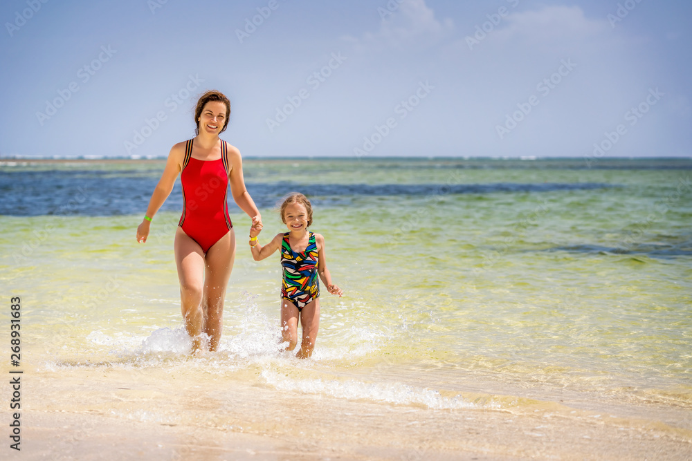 Young mother and little daughter running on the beach in Dominican Republic