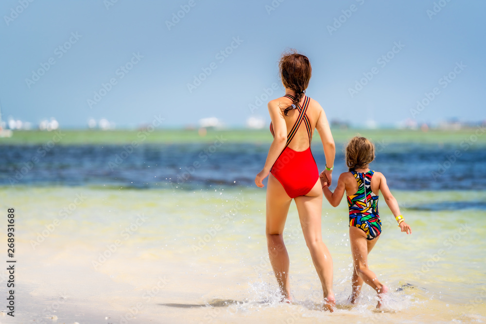 Young mother and little daughter running on the beach in Dominican Republic