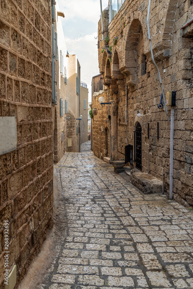 An old city narrow alley with stone walls and stone pavers