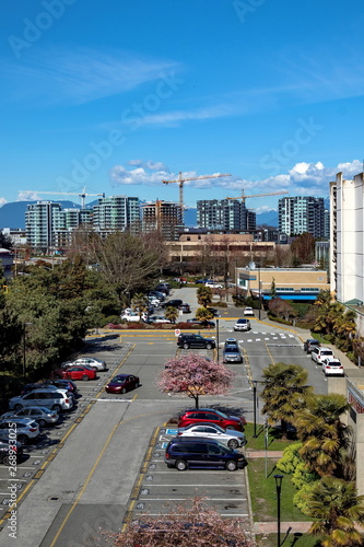 New construction of high-rise buildings in Richmond city, industrial construction site, construction equipment, several construction cranes  on the background of mountain range and a blue cloudy sky.  © Alex Lyubar