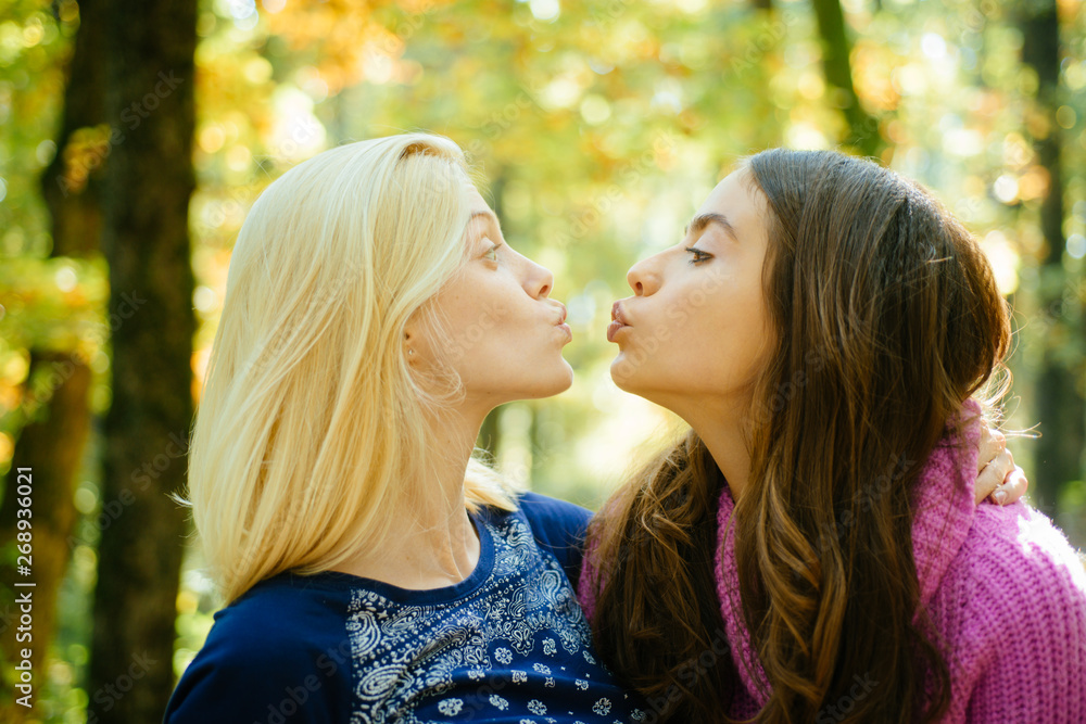 Friendly kiss. Glad to see you. Girls friends kissing. Girlish friendship concept. Blonde and brunette walking in autumn park defocused background. Women kiss cute faces close up. Come on kiss me Friendly kiss. Glad to see you. Girls friends kissing. Girlish friendship concept. Blonde and brunette walking in autumn park defocused background. Women kiss cute faces close up. Come on kiss me