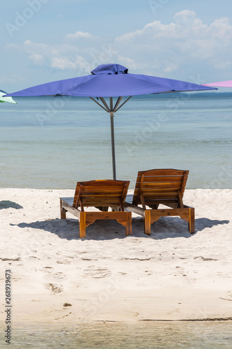 Vertical photo of chair and umbrella on the white sand beach