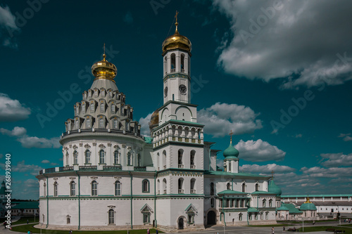 Orthodox New Jerusalem Monastery made of white stone with golden domes and turquoise rooftops against a blue sky. Famous Landmark near Moscow