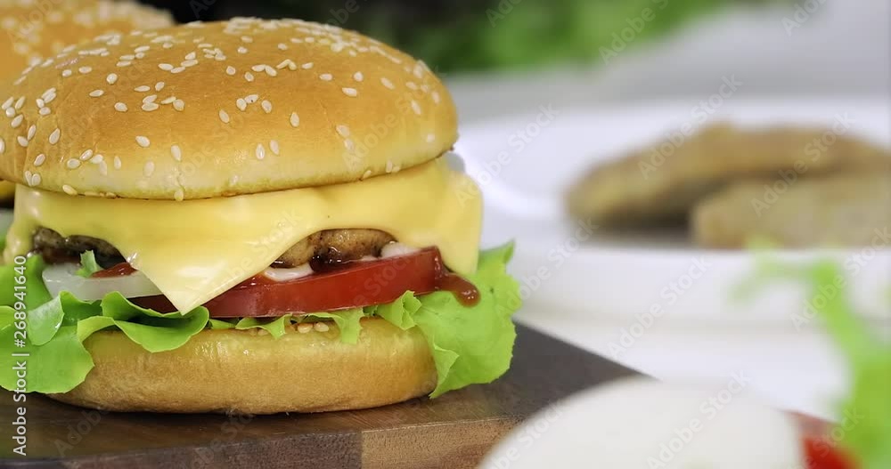 Zoom out scene video of cheese burger with slice tomato, onion, meat and lettuce, it looks delicious, blurred background. Zoom out scene video of cheese burger with slice tomato, onion, meat and lettuce, it looks delicious, blurred background.
