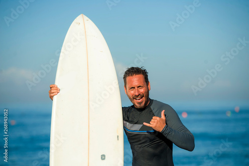 Photography handsome and attractive surfer man in neoprene swimsuit holding surf board posin