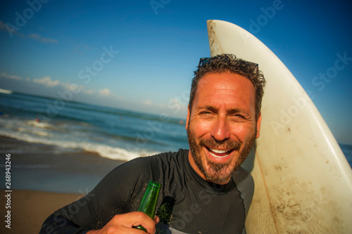 Photography attractive surfer man in neoprene swimsuit holding surf board posing cool and ha