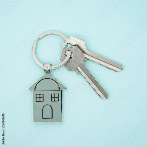 key chain with house symbol and keys on blue background,Real estate concept