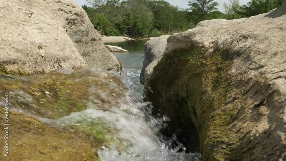 Flowing water cascades through eroded rock before it becomes a waterfall. Slow motion pulling back at water surface level revealing rocks and mosses. Flowing water cascades through eroded rock before it becomes a waterfall. Slow motion pulling back at water surface level revealing rocks and mosses.