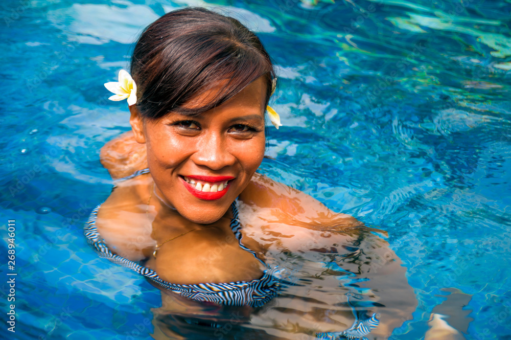 outdoors lifestyle portrait of middle aged 40s or 50s attractive and happy Asian Indonesian woman in biking enjoying holidays at Bali villa or tropical resort swimming pool