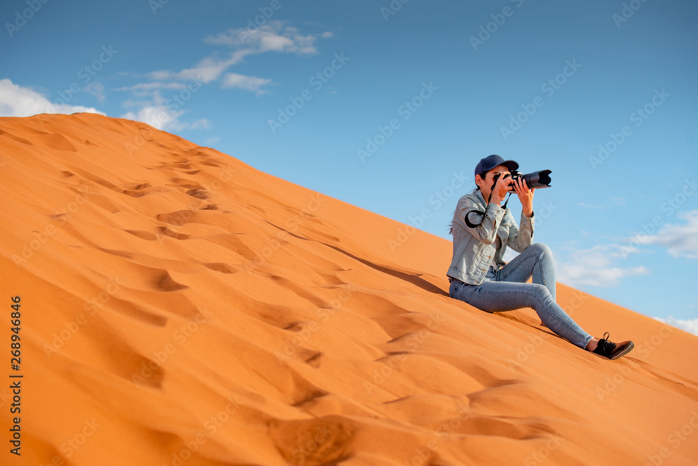 Φωτογραφία Young Asian woman traveler and photographer holding camera taking photo while sitting on sand dune in Namib desert of Namibia, Africa