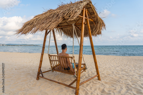 Fototapeta Naklejka Na Ścianę i Meble -  Young man relax on the swing on the beach