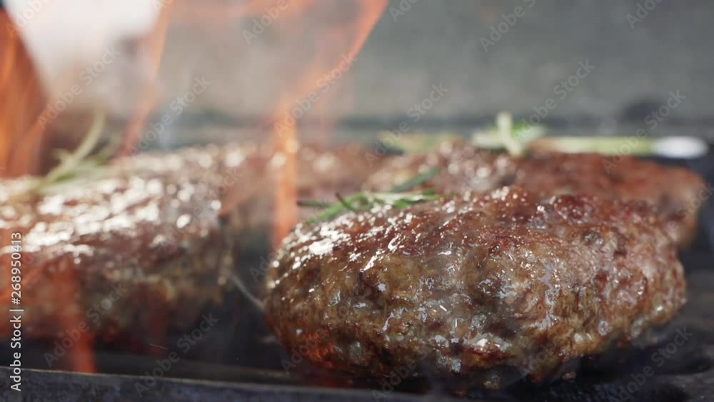 Tasty meat for a burger a barbecue grill. Fire is burning and juicy steak with stripes are become to be ready. Close up of chief cooked tasty burger in casual bar slow motion Tasty meat for a burger a barbecue grill. Fire is burning and juicy steak with stripes are become to be ready. Close up of chief cooked tasty burger in casual bar slow motion