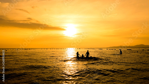 The silhouette people in the sea at the evening sunset © Phawat