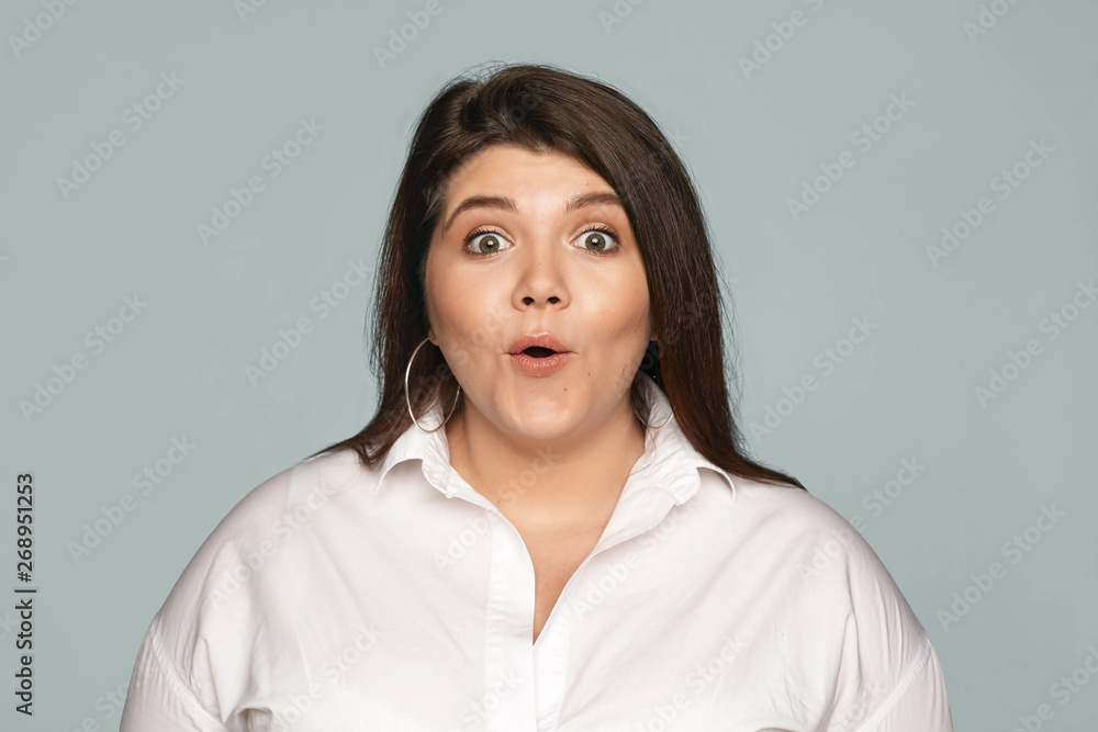 Emotional obese chubby young brunette female employee in formal shirt opening mouth expressing full disbelief, receiving unexpected raise in salary. Human facial expressions, feelings and reaction Emotional obese chubby young brunette female employee in formal shirt opening mouth expressing full disbelief, receiving unexpected raise in salary. Human facial expressions, feelings and reaction