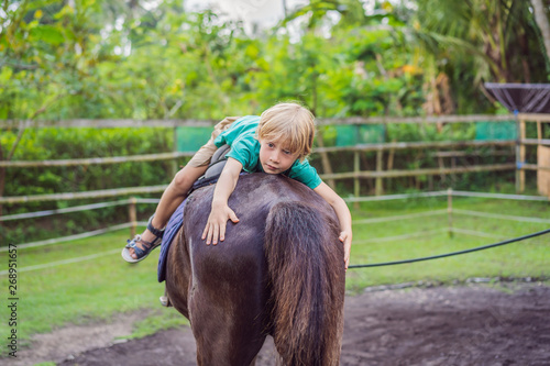 Boy horseback riding, performing exercises on horseback