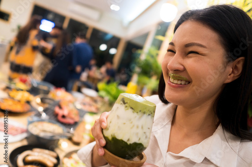 Beautiful Adult working woman drink Ice Milky Green Tea and smile with foam on her lips  atmosphere with many food plates and people in restaurant, selective focus blur photo