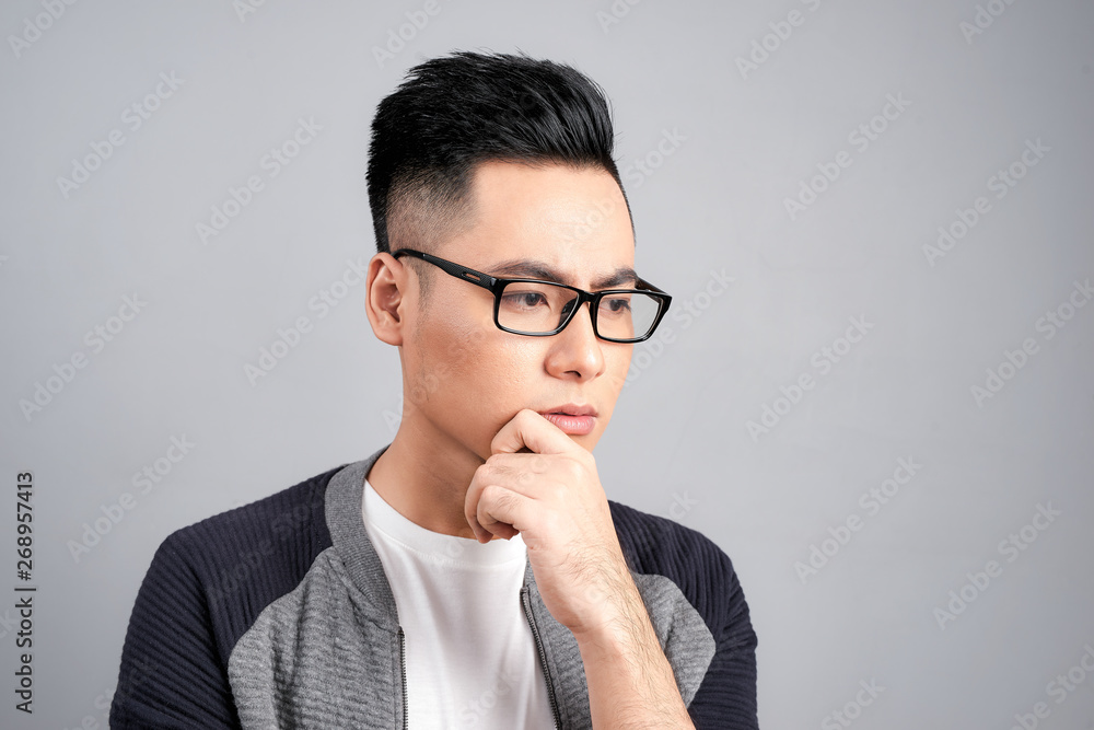 Studio shot of young Asian man thinking while wearing eyeglasses Studio shot of young Asian man thinking while wearing eyeglasses