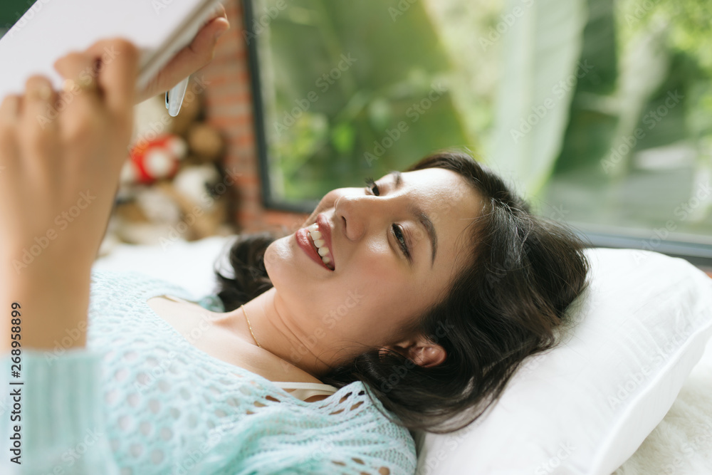 Fototapeta premium Beautiful young asian woman laying on bed and writing a diary.
