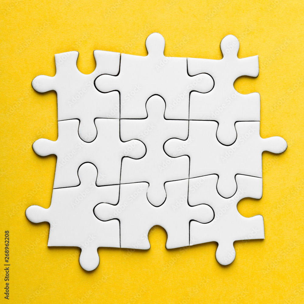 Fototapeta premium Connected blank puzzle pieces on a yellow background.