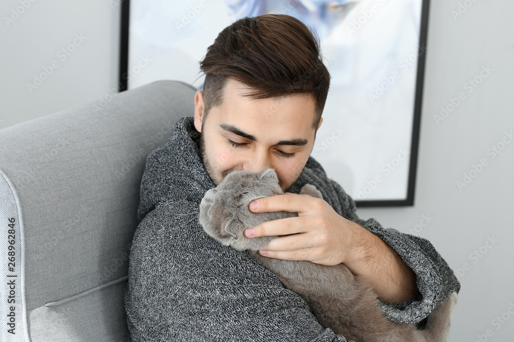 Young man with cute funny cat at home Young man with cute funny cat at home