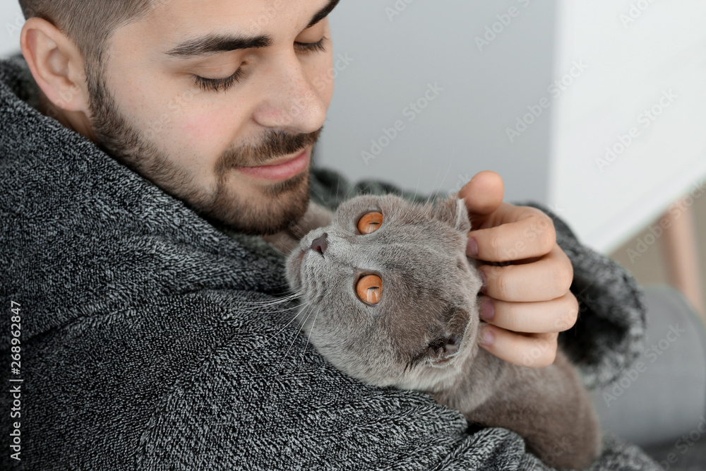 Young man with cute funny cat at home Young man with cute funny cat at home