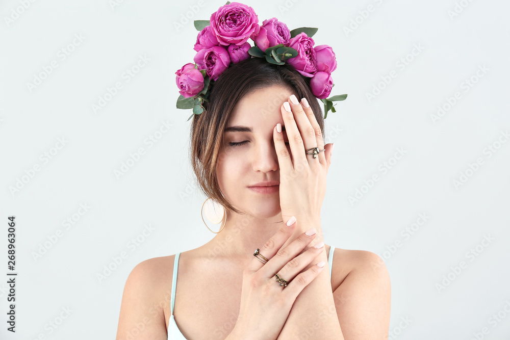Young woman with beautiful flowers on her head on light background Young woman with beautiful flowers on her head on light background