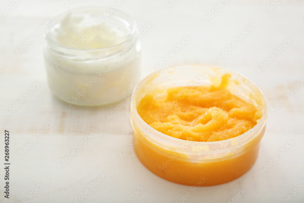 Jar with orange body scrub on light table Jar with orange body scrub on light table