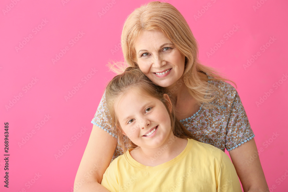 Mature woman and her cute granddaughter on color background Mature woman and her cute granddaughter on color background