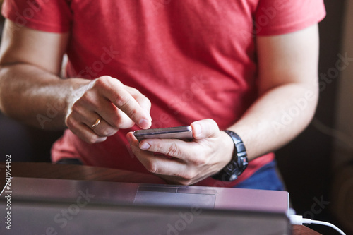 Man using smartphone working on laptop