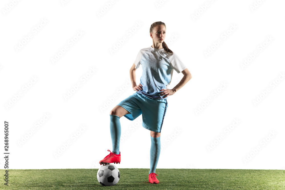 Young female football or soccer player with long hair in sportwear and boots standing with the ball isolated on white background. Concept of healthy lifestyle, professional sport, hobby.