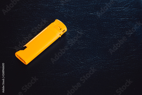 on a blue leather surface is a bright yellow lighter