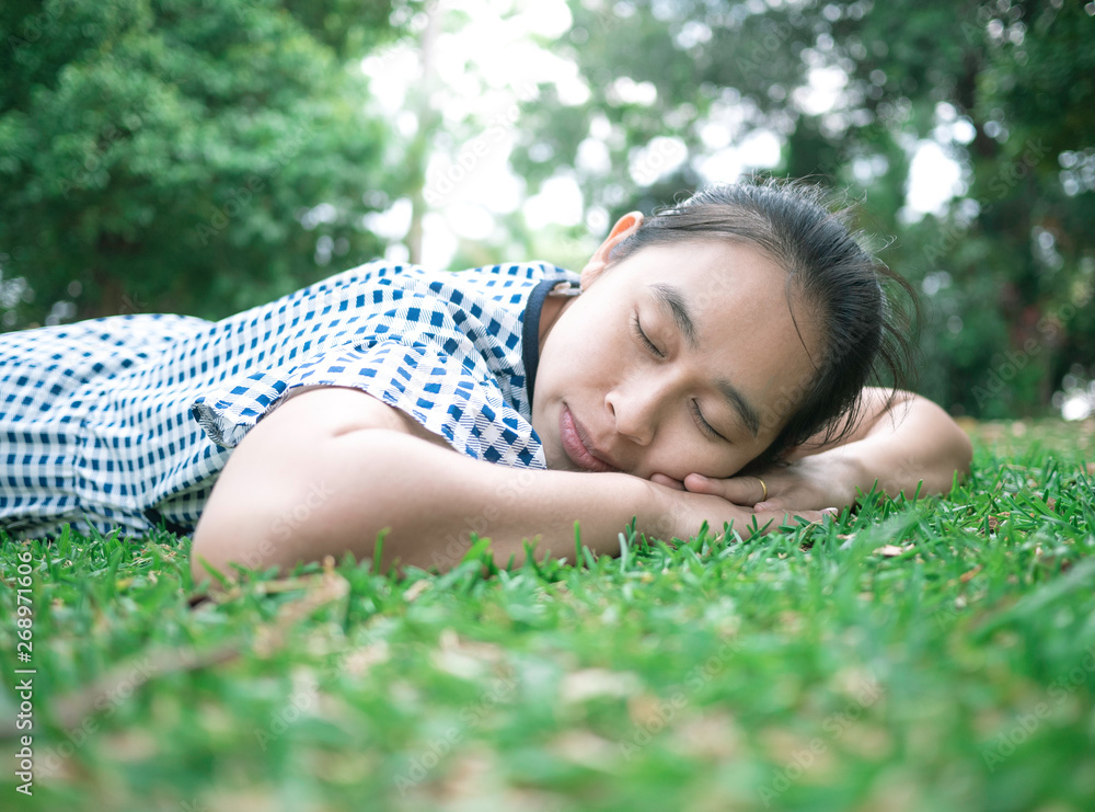 Asian young woman lying down on grass ground in the park for relaxation time. Space for your text. Asian young woman lying down on grass ground in the park for relaxation time. Space for your text.
