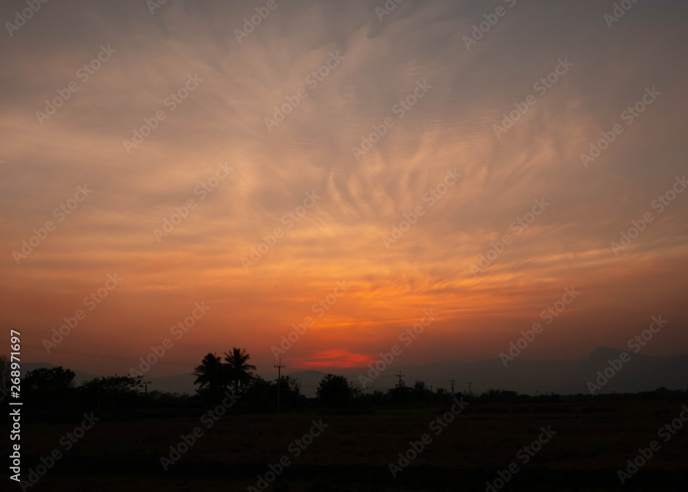 View of Sunset over rice field; Bright dramatic sky and dark ground in countryside Landscape.