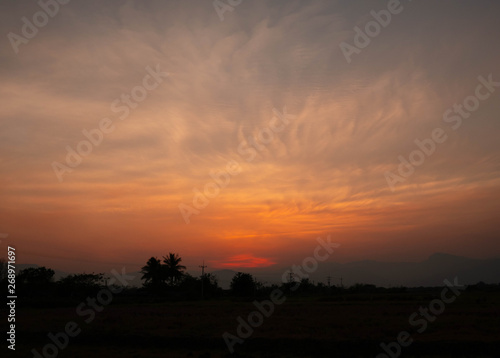 View of Sunset over rice field; Bright dramatic sky and dark ground in countryside Landscape.