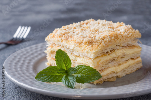 Layered cake with cream Napoleon millefeuille vanilla slice with mint on dark background. photo