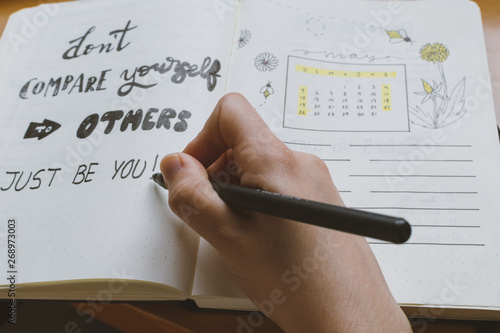 hand of a person writing on bullet journal a self-esteem quote. Beautiful calligraphy