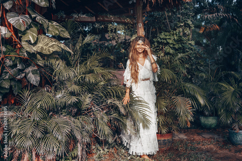 beautiful young cheerful boho style woman at tropical green leaves background