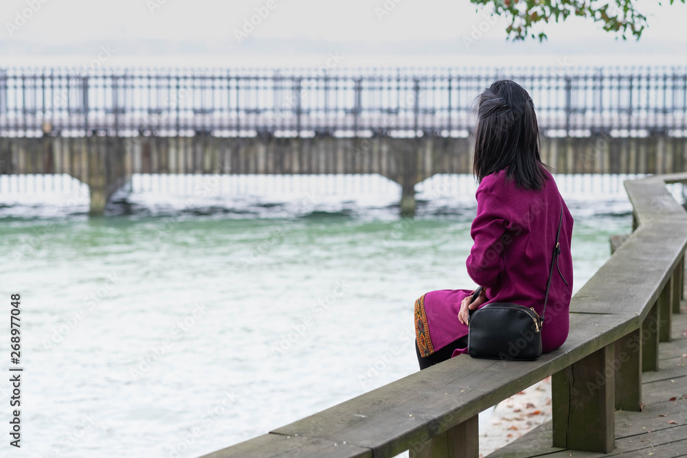 Unspecific young girl is looking at the East lake.