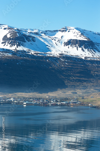 View to the small town and snowy mountains in the fjord of Iceland