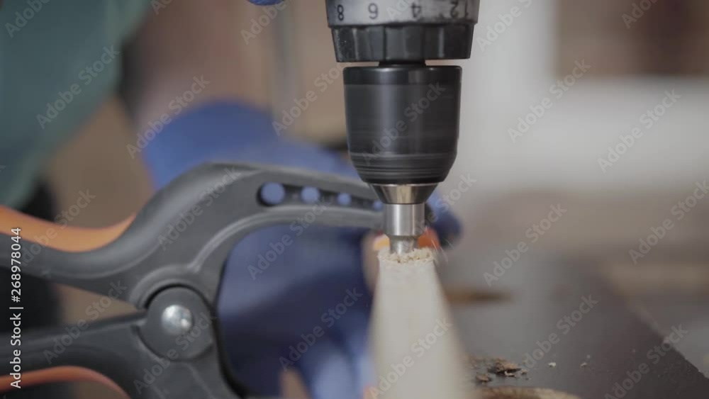 Unrecognized skill kraftsman making halls in the chipboard details with cordless screwdriver. Concept of hand manufacturing. Craftman works in a workshop. Unrecognized skill kraftsman making halls in the chipboard details with cordless screwdriver. Concept of hand manufacturing. Craftman works in a workshop.