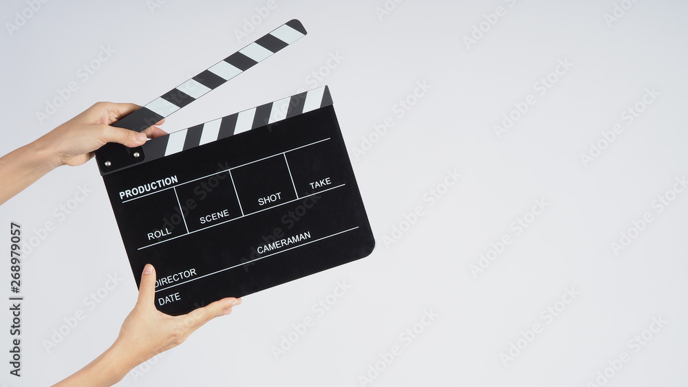 Naklejka premium Hands is holding black Clapperboard or movie slate. it use in video production ,film, cinema industry on white background.