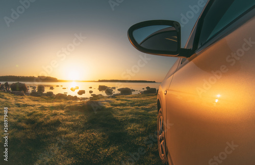 Morning landscape. The sun rises over the lake. Focus on the car.