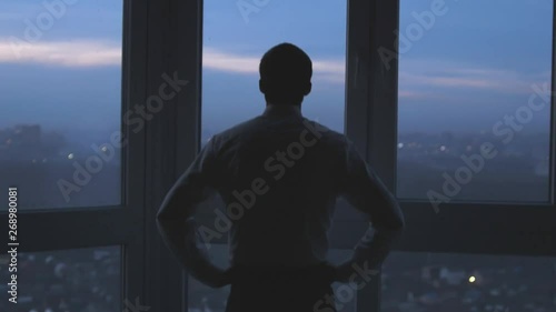 Back view of the thoughtful businessman wearing a suit looking out of the panoramic window. slow motion. 3840x2160