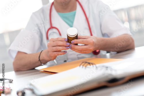 Female doctor looking at a bottle of pills