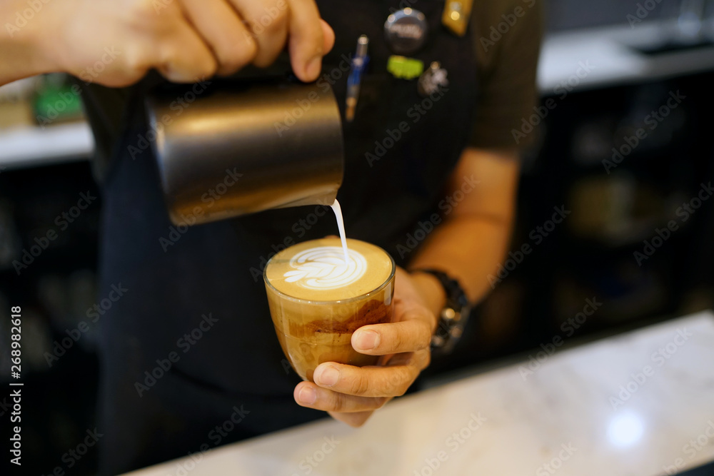 Barista making coffee with latte art, Created by pouring steamed milk into a shot of espresso and resulting in a pattern or design on the surface of the latte. Barista making coffee with latte art, Created by pouring steamed milk into a shot of espresso and resulting in a pattern or design on the surface of the latte.