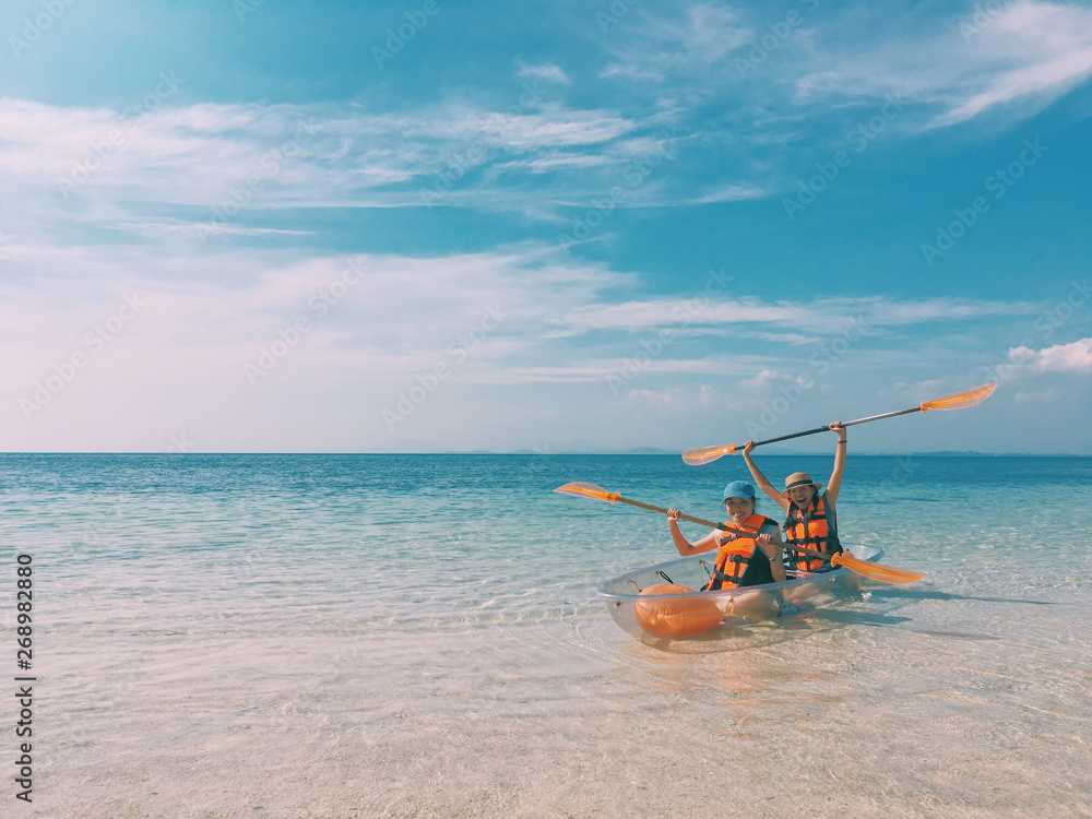 Asian Woman tourists are kayaking in the blue sea to the island in Thailand.Concept of travel in summer holiday. Asian Woman tourists are kayaking in the blue sea to the island in Thailand.Concept of travel in summer holiday.